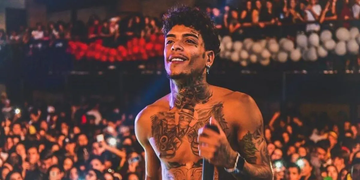 MC Kevin em show sorridente e com microfone na mão para um grande público.