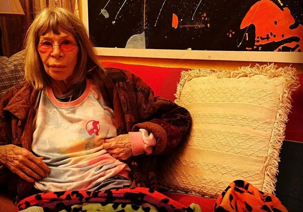 Foto da cantora Rita Lee sentada em um sofá