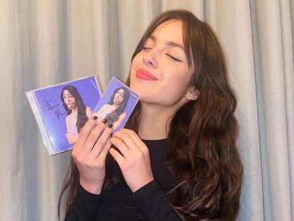 Olívia Rodrigo segurando seu álbum de lançamento Sour