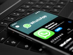 Whatsapp na tela de um celular, que está apoiado no teclado de um notebook