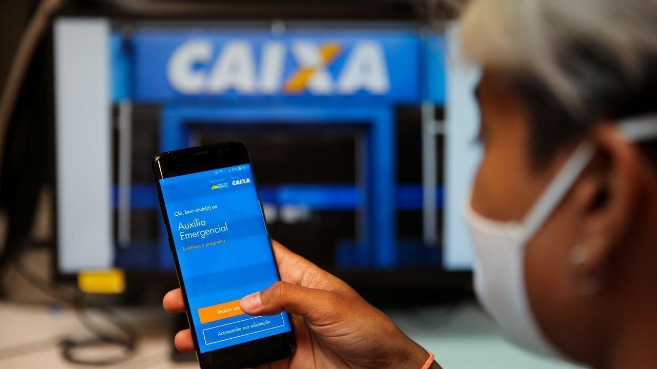 Beneficiário em frente a uma agência utilizando o app do auxílio