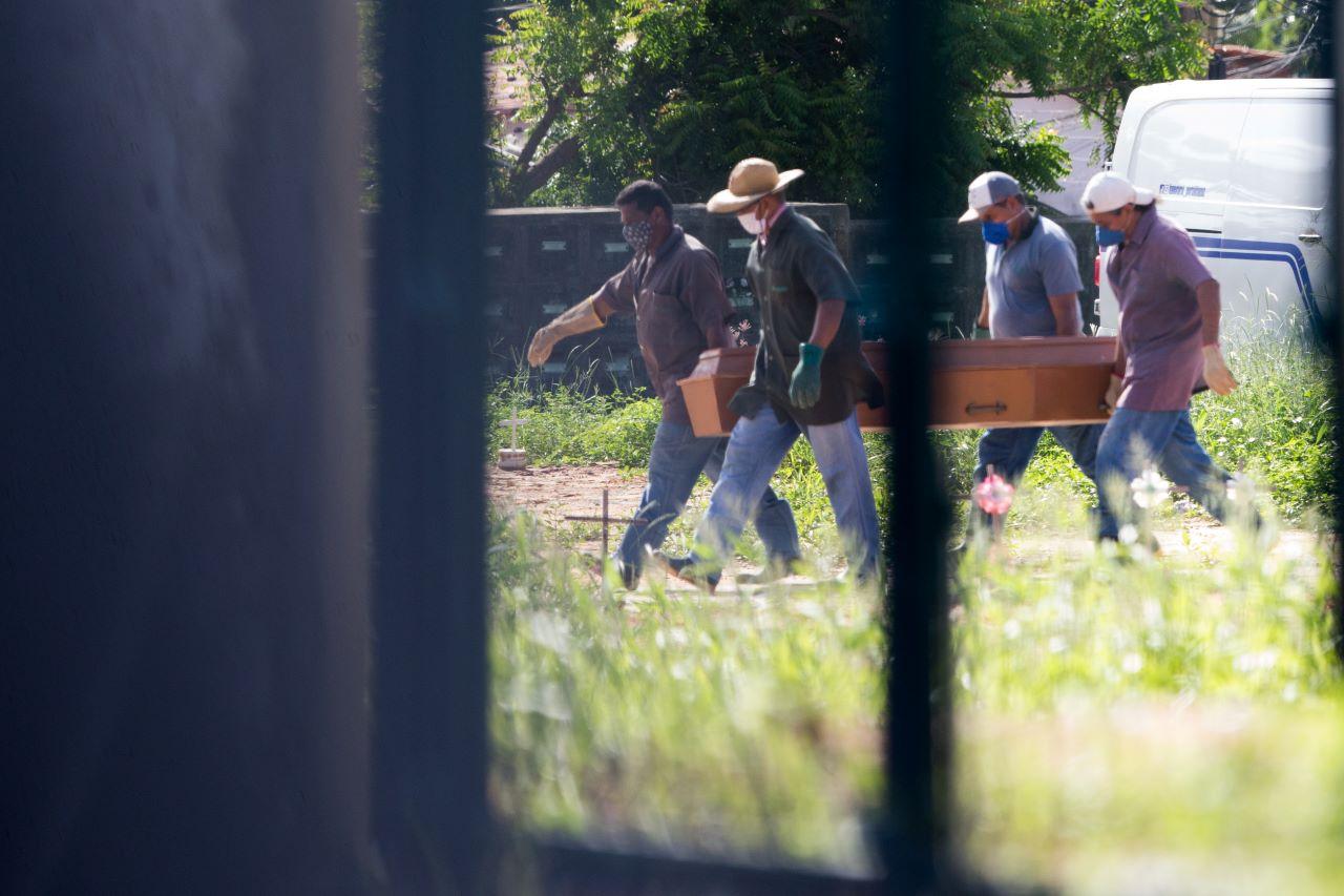 homens carregam caixão em cemitério