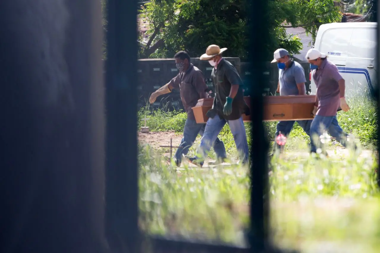 homens carregam caixão em cemitério
