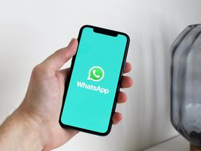 Mão de pessoa segurando o celular com tela do Whatsapp