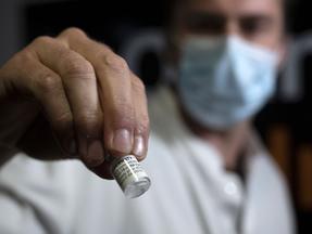 homem segura frasco da vacina da pfizer, comirnaty