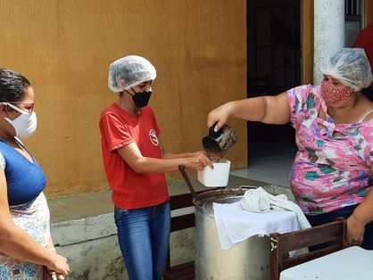Mulher despeja alimento em vasilha de plástico em ação de combate à fome