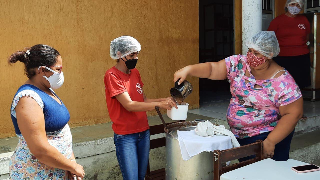 Mulher despeja alimento em vasilha de plástico em ação de combate à fome