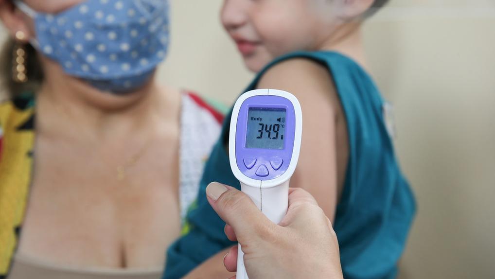Medidor de temperatura sendo colocado em braço de criança
