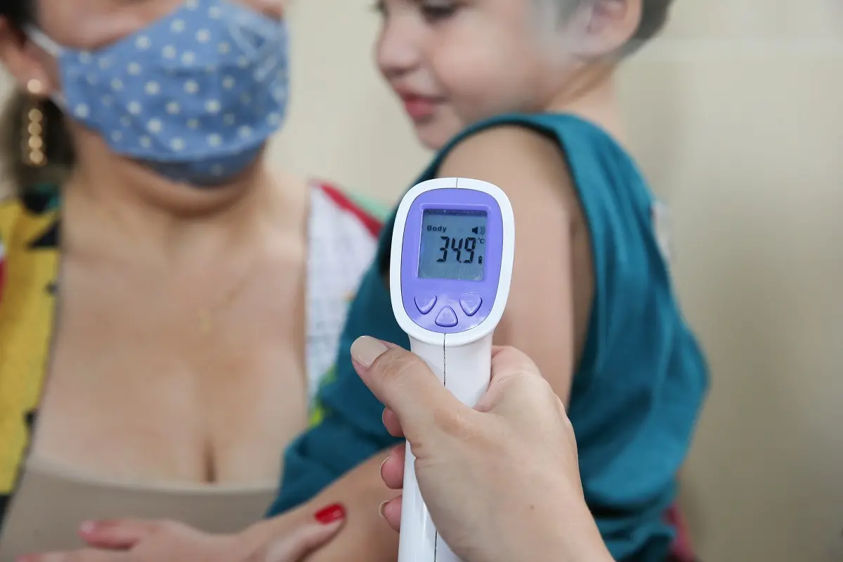 Medidor de temperatura sendo colocado em braço de criança