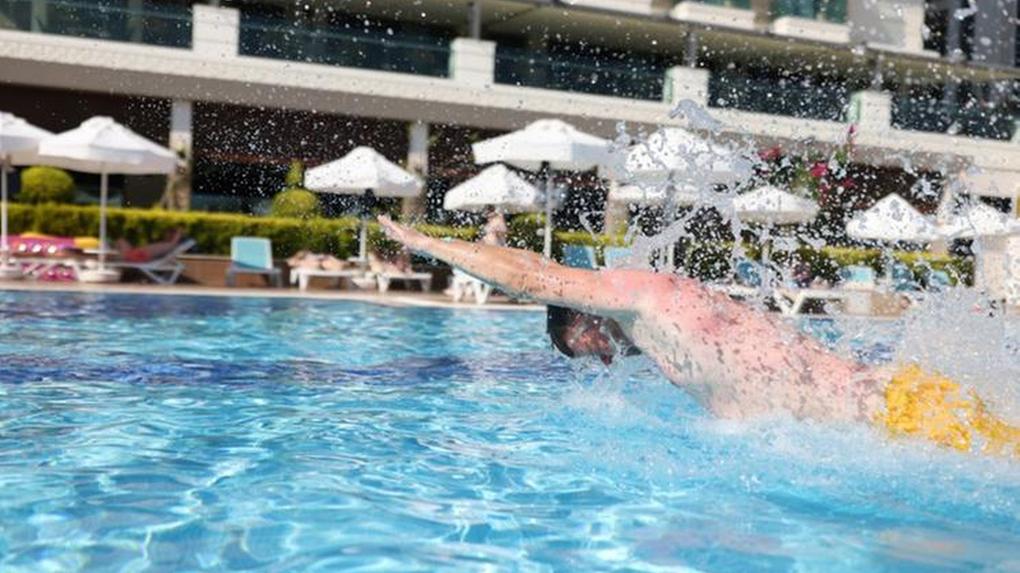 Foto: homem nadando em piscina de hotel