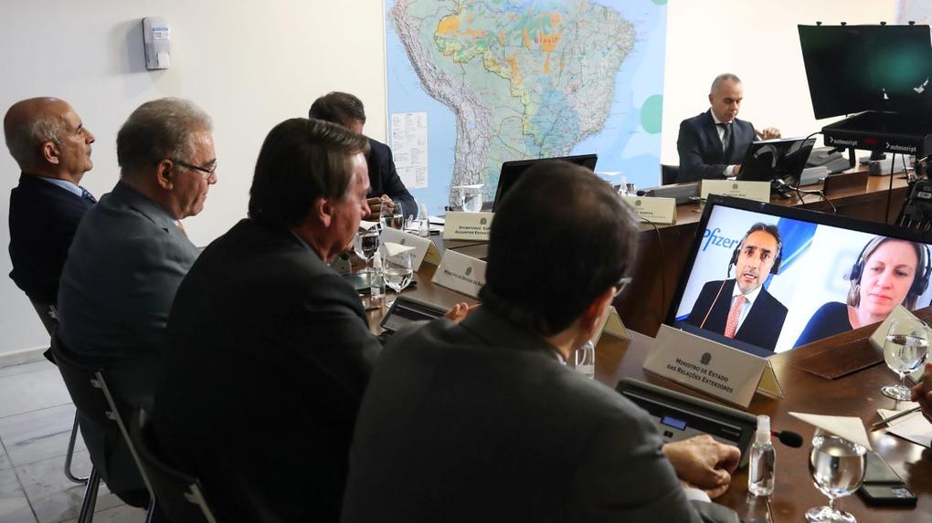 presidente e ministros diante de tela onde aparecem representantes da pfizer participando por videoconferência da reunião