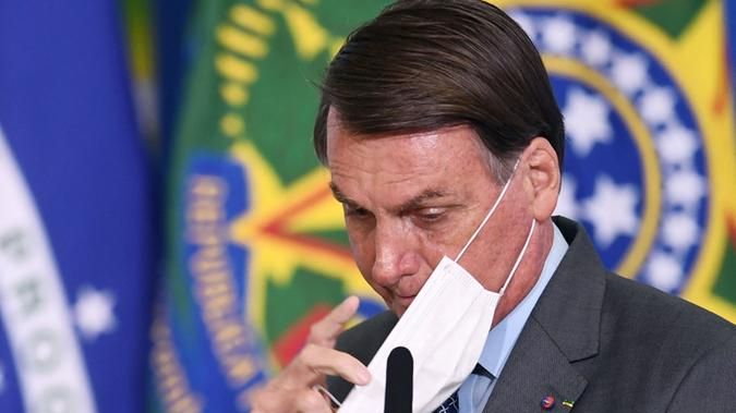 Presidente Jair Bolsonaro ajustando a máscara no rosto