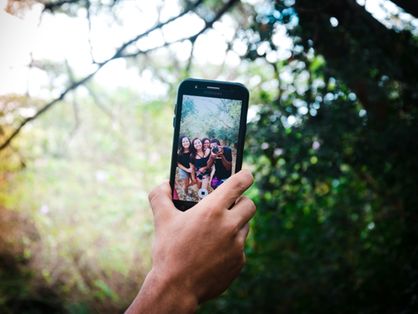 mão segurando celular com foto de amigos