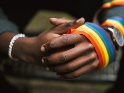 Mãos negras com faixa com cores do arco-íris na mão