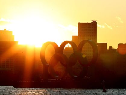 Imagem do pôr do sol com o arco olímpico na frente em Tóquio