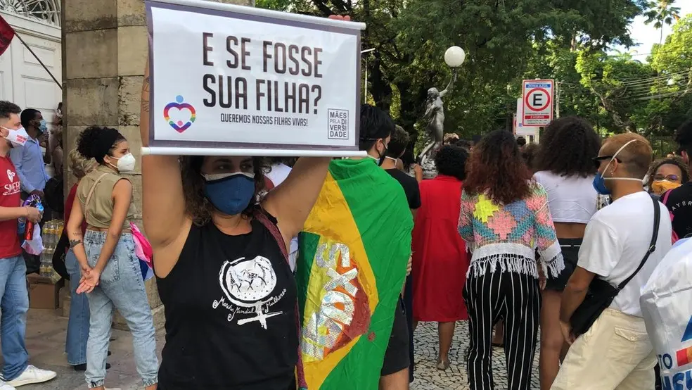 Manifestante segurando placa com frase 