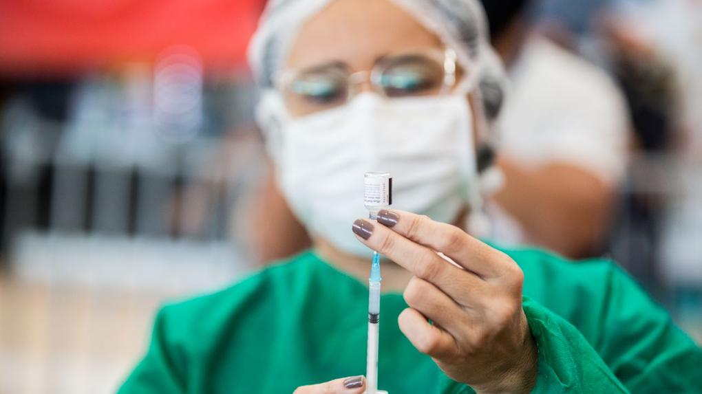 profissional de saúde coloca vacina em seringa