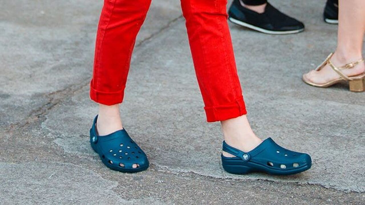 Pessoa de calça vermelha usando um par de Crocs