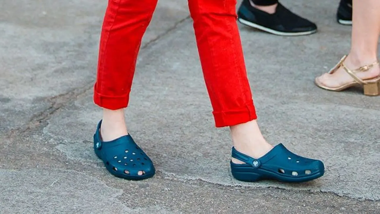 Pessoa de calça vermelha usando um par de Crocs