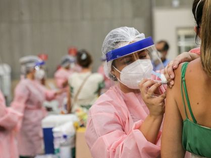 Mulher sendo vacinada por profissional da saúde no Centro de Eventos do Ceará