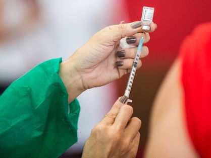 Mãos de enfermeira segurando ampola com vacina contra Covid-19