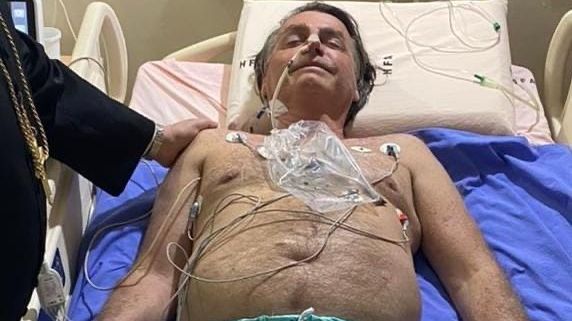 Bolsonaro deitado em maca de hospital com aparato médico