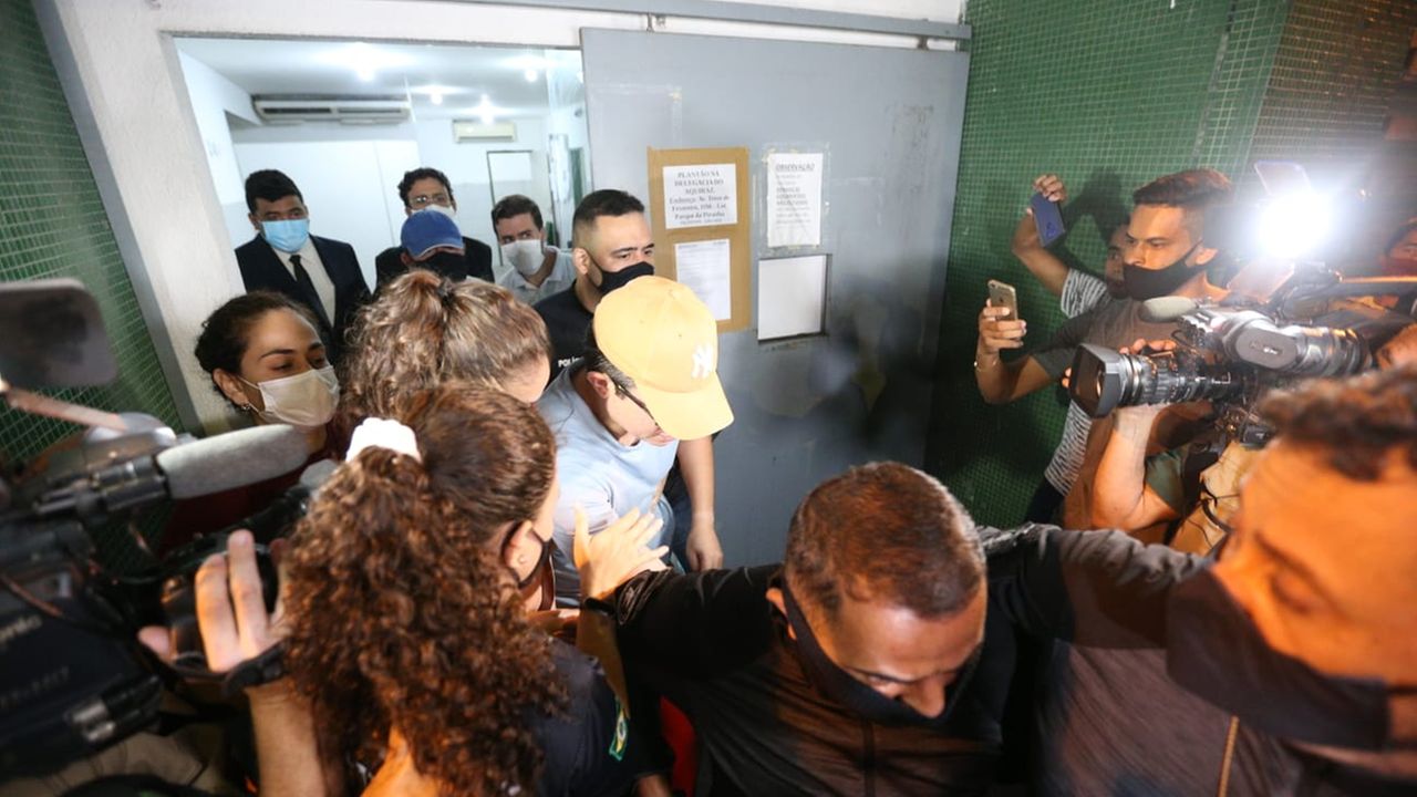 de boné, dj ivis deixa a delegacia metropolitana do eusébio cercado por policiais e profissionais da imprensa