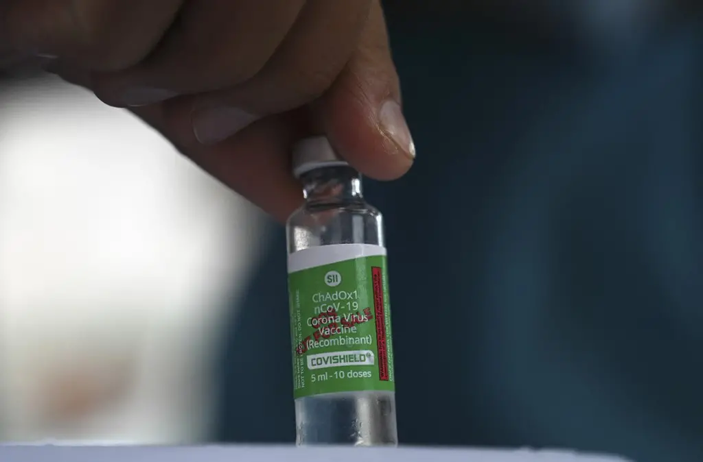 Mão segurando frasco da vacina AstraZeneca