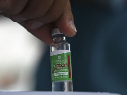 Mão segurando frasco da vacina AstraZeneca