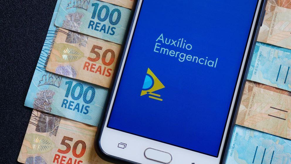 Celular com aplicativo do auxílio emergencial sobre valor em dinheiro
