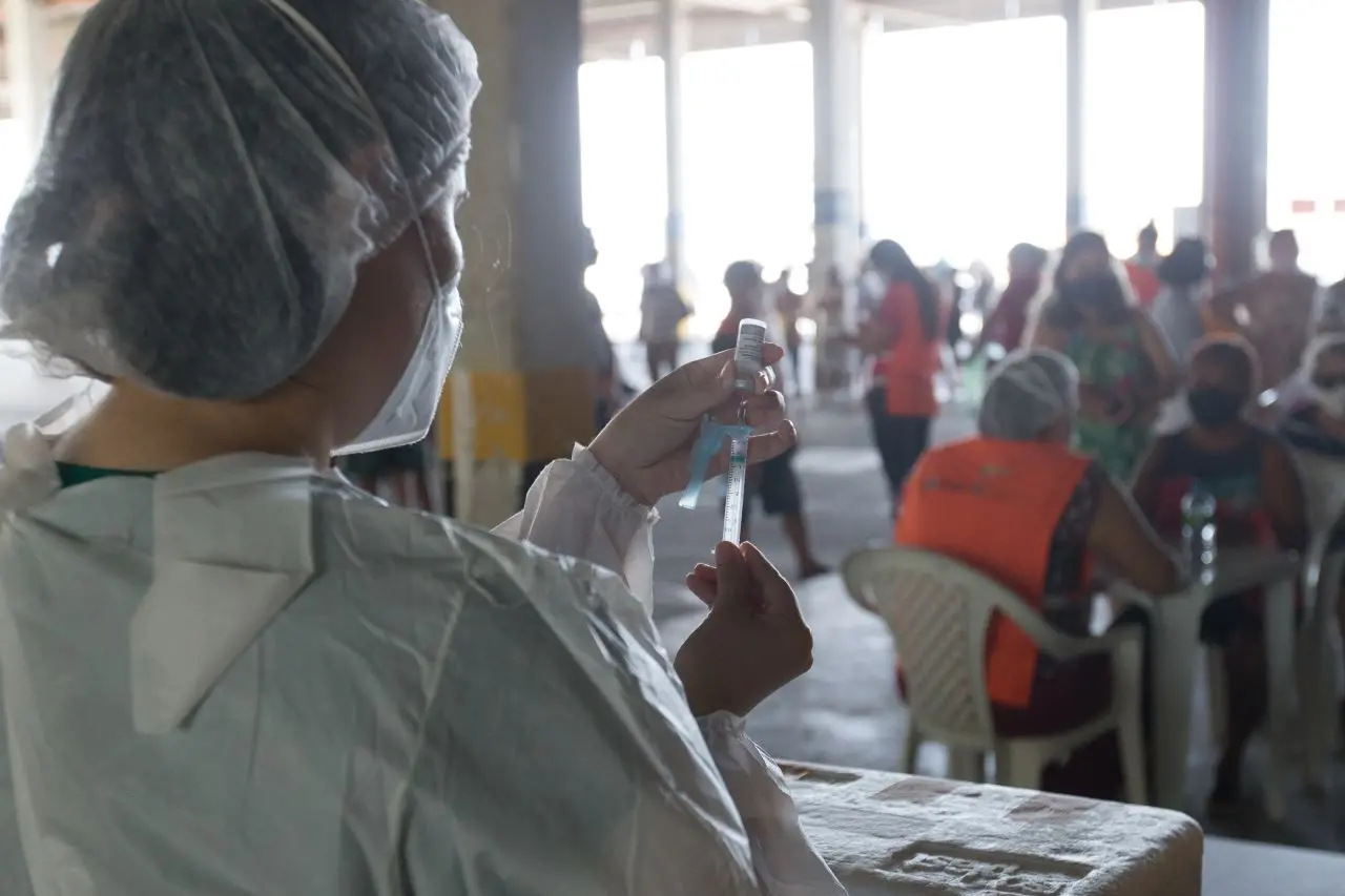 profissional coloca dose de vacina em seringa