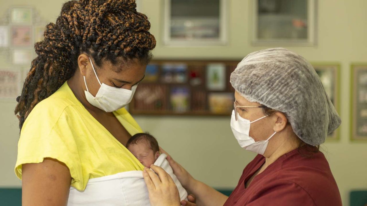 Profissional de saúde acolhendo puérpera com bebê no colo