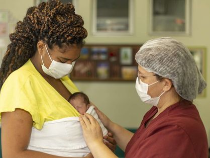 Profissional de saúde acolhendo puérpera com bebê no colo