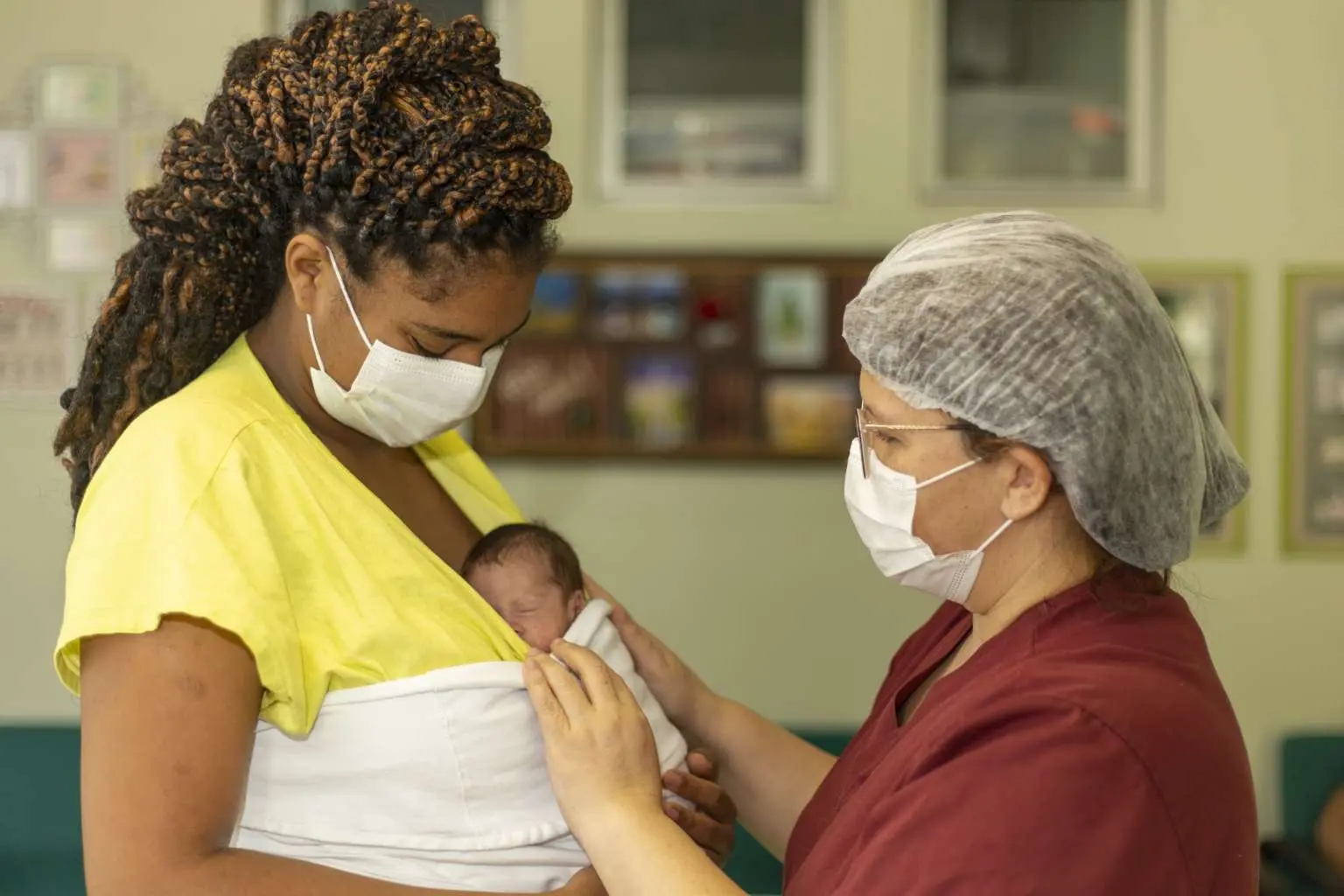 Profissional de saúde acolhendo puérpera com bebê no colo