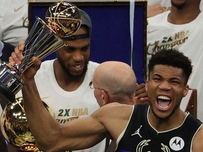 Giannis Antetokounmpo segura o troféu de campeão da NBA e comemora vitória