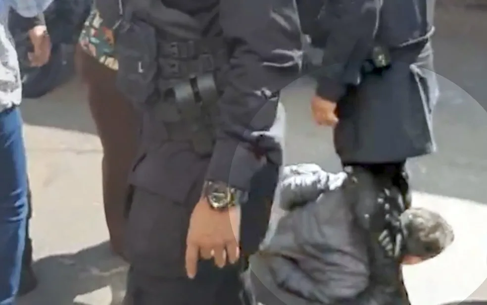 Um dos vídeos mostra o advogado levando uma tapa no rosto enquanto já estava contido. Logo depois, ele aparece com o pescoço preso entre as pernas do PM