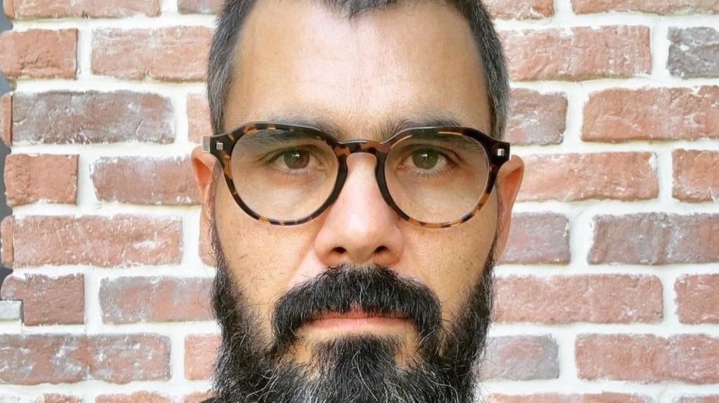 Ator Juliano Cazarré de blusa preta e óculos