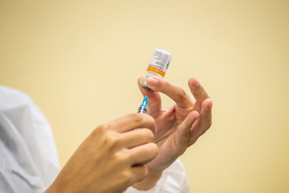 Enfermeira segurando dose da coronavac