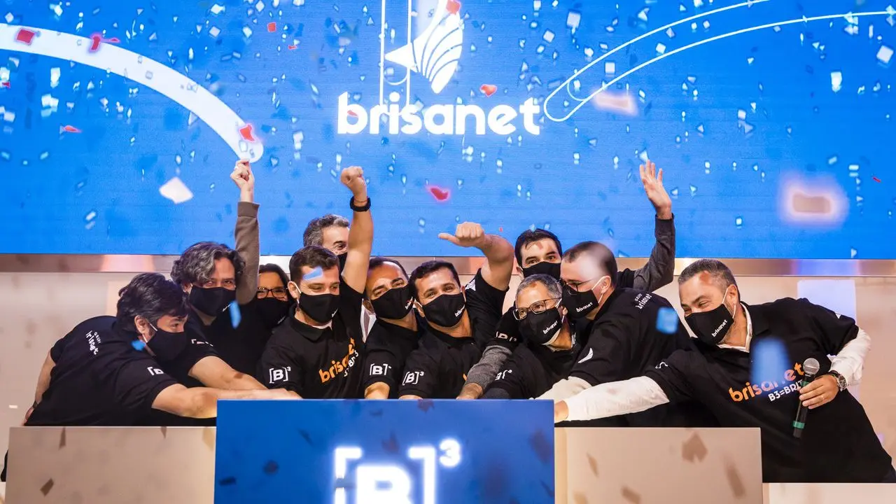 pessoas comemorando ipo com o logo da brisanet ao fundo