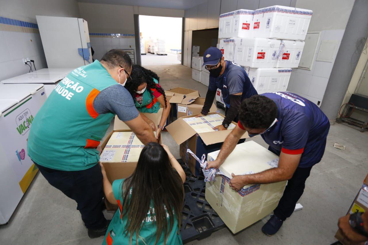Pessoas desembarcando lotes de vacinas contra Covid-19