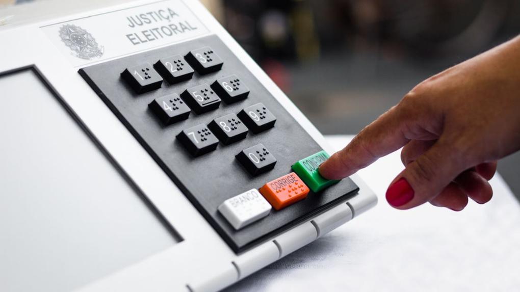 Mão votando em urna eletrônica