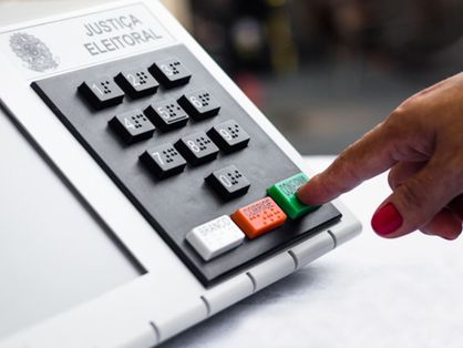 Mão votando em urna eletrônica