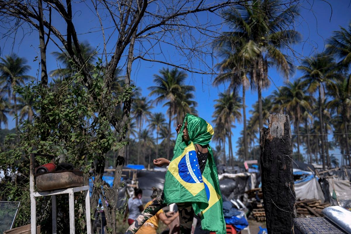 Menina enrolada em bandeira do Brasil em meio à pobreza