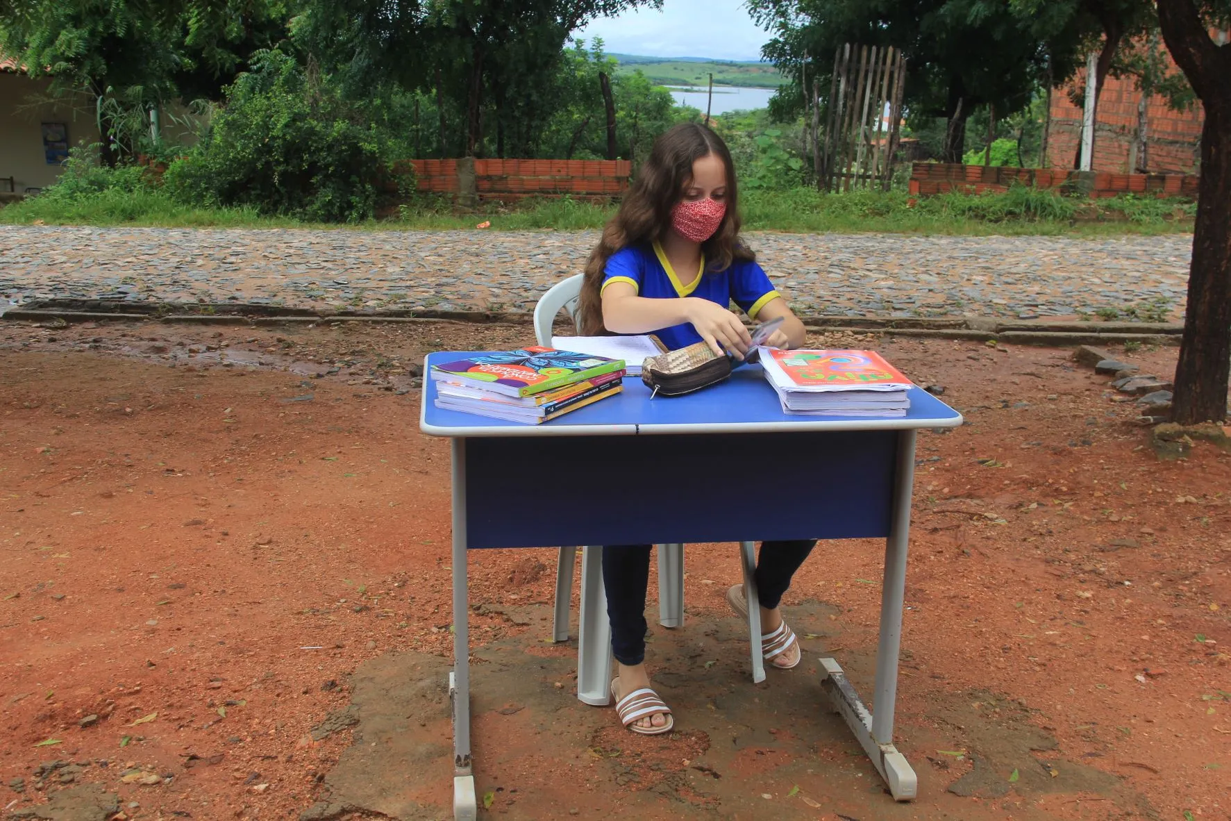 A aluna Ingrid Bezerra, que mora na Localidade de Ubaldinho, Zona Rural de Cedro; estuda na calçada, em frente à casa dela para ter um sinal melhor de internet
