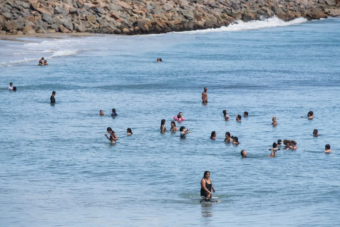 pessoas dentro do mar da praia de iracema