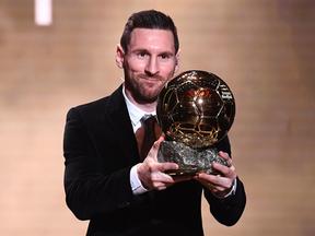 Messi sorri e mostra o prêmio de Bola de Ouro