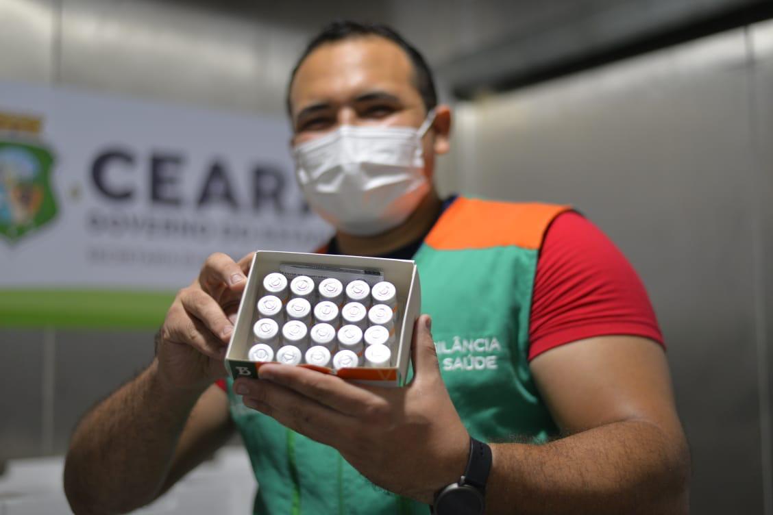 Homem segura frascos da vacina coronavac