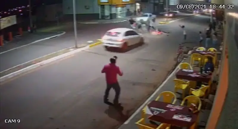 Imagem de câmera de segurança mostrando Gol branco na direção de grupo de pessoas e ciclista