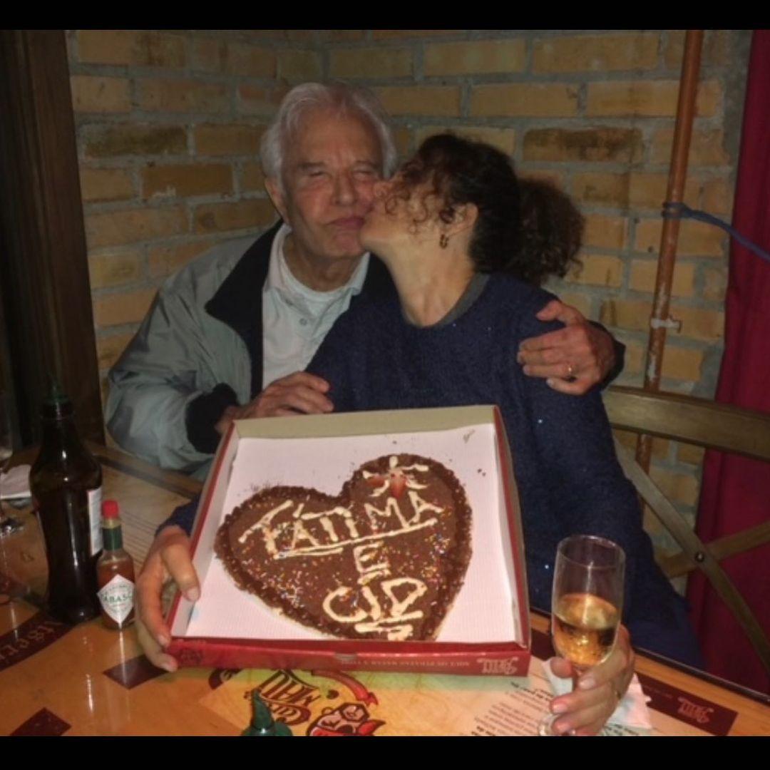 Fátima beijando Cid enquanto segura pizza de chocolate em forma de coração, na qual nomes do casal estão inscritos