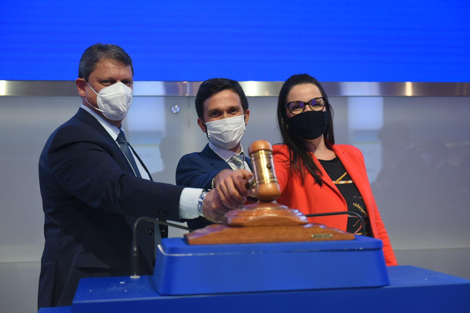 Dois homens e uma mulher batendo um martelo de leilão